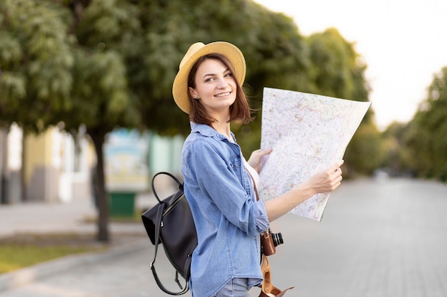 Szczęśliwy podróżnik z kapeluszową trzyma lokalną mapą