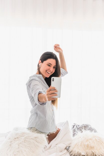 Szczęśliwy portret młoda kobieta bierze selfie na smartphone