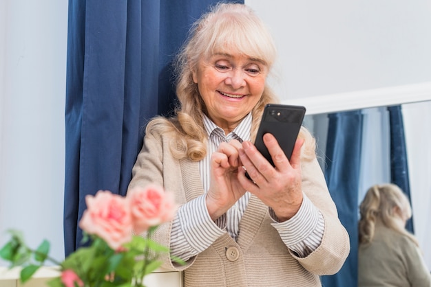 Szczęśliwy portret starsza kobieta używa telefon komórkowego
