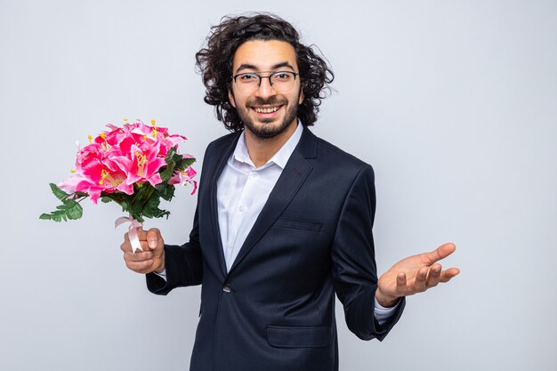 Szczęśliwy przystojny mężczyzna w garniturze z bukietem kwiatów, uśmiechający się radośnie