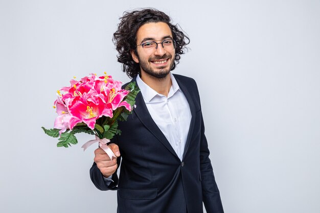 Szczęśliwy przystojny mężczyzna w garniturze z bukietem kwiatów, uśmiechający się radośnie