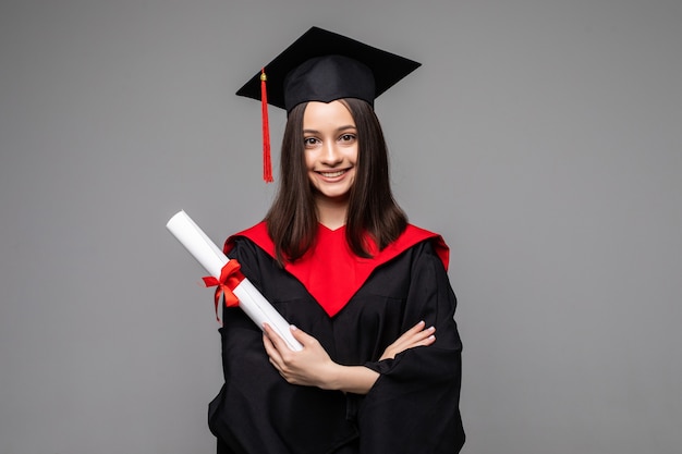 Szczęśliwy student z czapką dyplomową i dyplomem na szaro