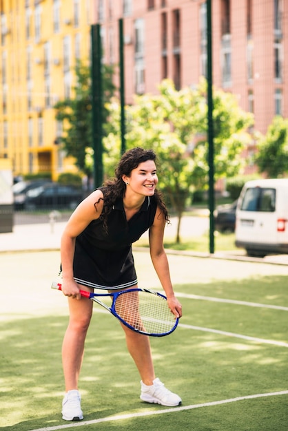 Szczęśliwy żeński gracz przy tenisowym sądem