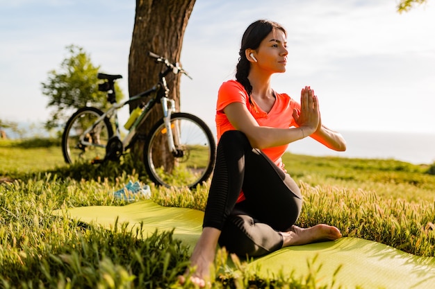 Bezpłatne zdjęcie szczupła piękna kobieta uprawiania sportu rano w parku robi joga