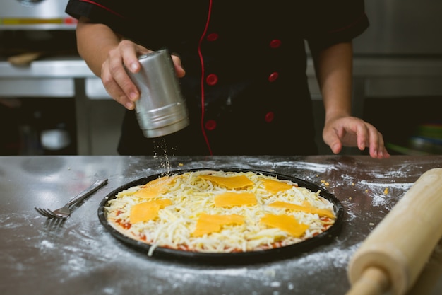 Bezpłatne zdjęcie szef kuchni robi pizzę w kuchni