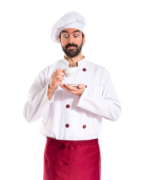 Szef kuchni trzyma filiżankę kawy na białym tle
