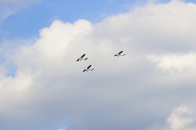 Szeroki kąt trzech samolotów lecących w trójkątnym wzorze za chmurami