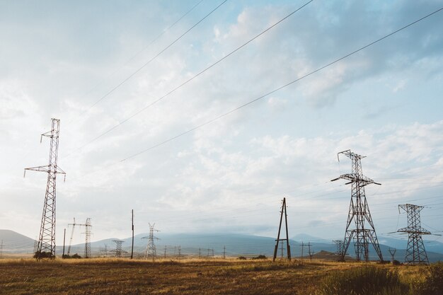 Szerokokątne ujęcie wielu słupów elektrycznych na suchym krajobrazie pod zachmurzonym niebem