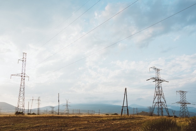 Szerokokątne ujęcie wielu słupów elektrycznych na suchym krajobrazie pod zachmurzonym niebem