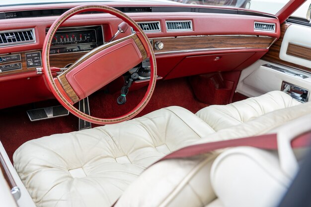 Szerokokątne ujęcie wnętrza samochodu, w tym czerwonej kierownicy i białych siedzeń