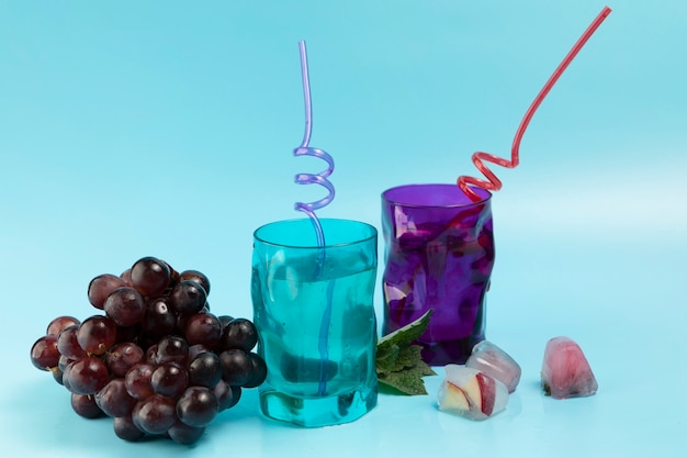 Bezpłatne zdjęcie szkła z wodnymi kostkami lodu i winogronami na błękitnym tle