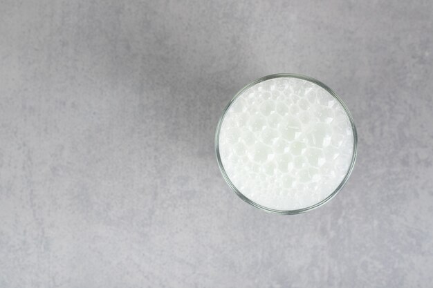 Szklanka czystej zimnej wody z bąbelkami na szarej powierzchni