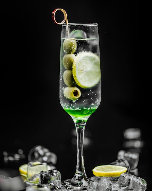 Szklanka martini z oliwkami i plasterkiem cytryny.