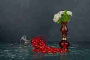 Bezpłatne zdjęcie szklanka nasion granatu i białych kwiatów w wazonie.