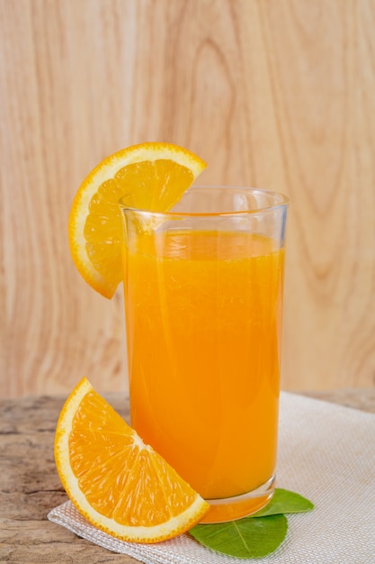 Szklanka soku pomarańczowego umieszczonego na drewnie.