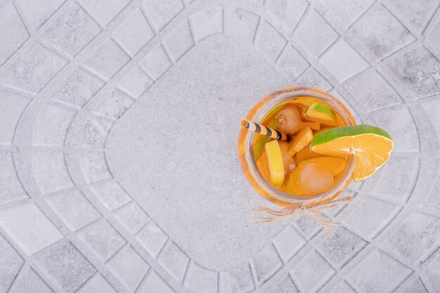 Szklanka soku z kawałkami owoców na marmurowym stole.