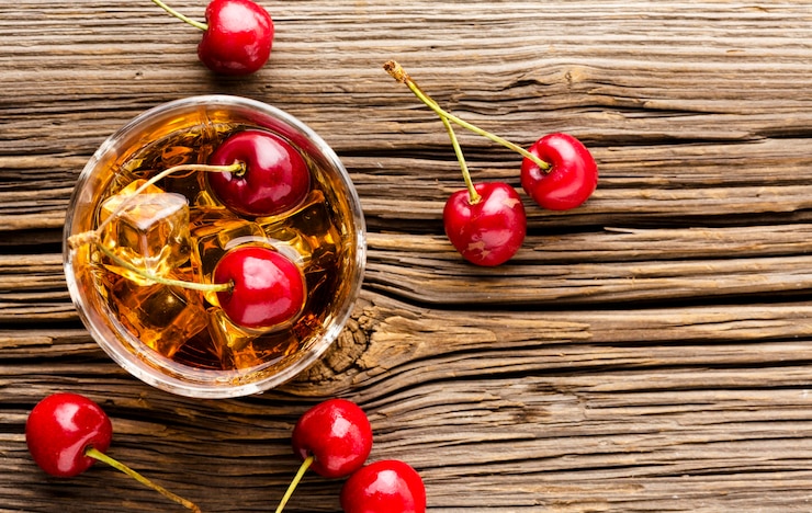 Bezpłatny plik Zdjęcie szklanka whisky z widokiem z góry z lodem i wiśniami