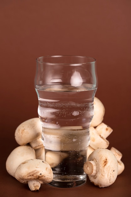 Szklanka wody w otoczeniu świeżych grzybów