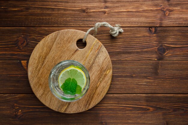 szklanka wody z cytryną na drewnianej desce do krojenia na powierzchni drewnianych