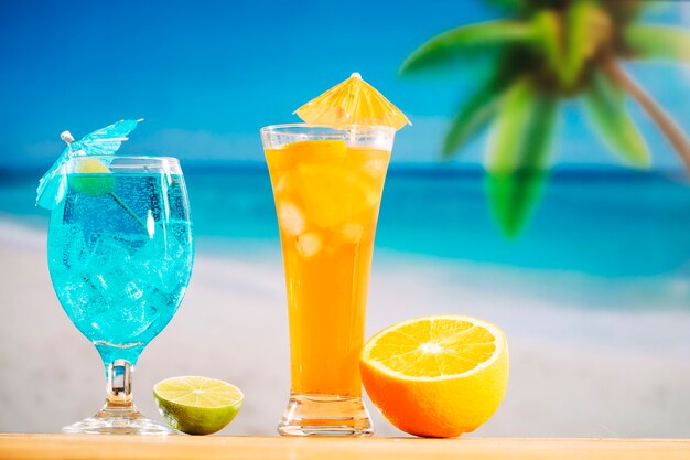 Szklanki świeżych napojów ozdobione oliwkowym parasolem i plasterkami limonki pomarańczowej