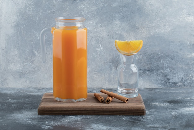 Bezpłatne zdjęcie szklany dzbanek świeżego soku i cynamonu na desce.