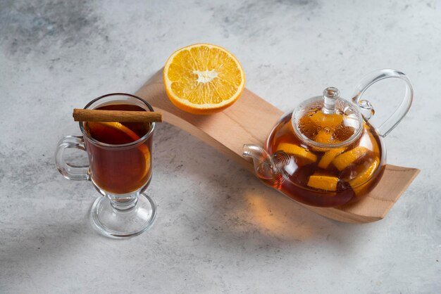 Szklany imbryk z herbatą i plasterkiem pomarańczy.