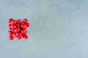 Bezpłatne zdjęcie szklany talerz pełen słodkich pysznych czerwonych cukierków na białej powierzchni