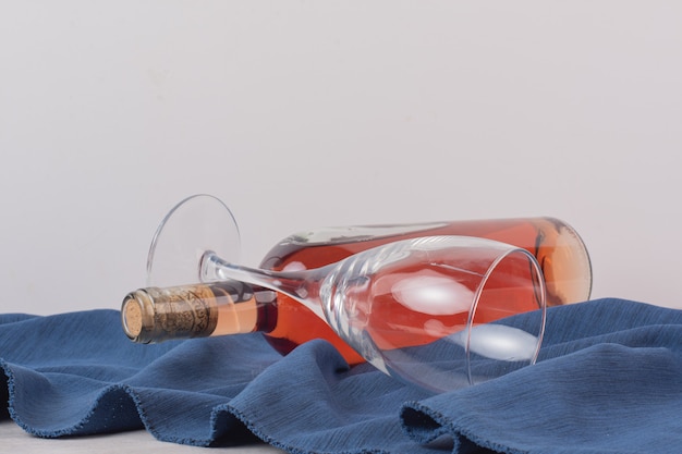 Szkło i butelka różowego wina na niebieskim obrusie.