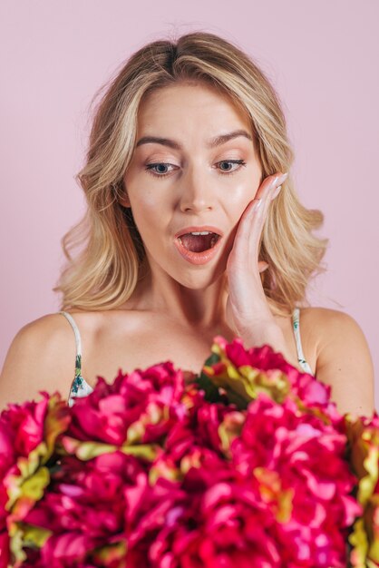 Szokująca blondynki młoda kobieta patrzeje kwiatu bukiet