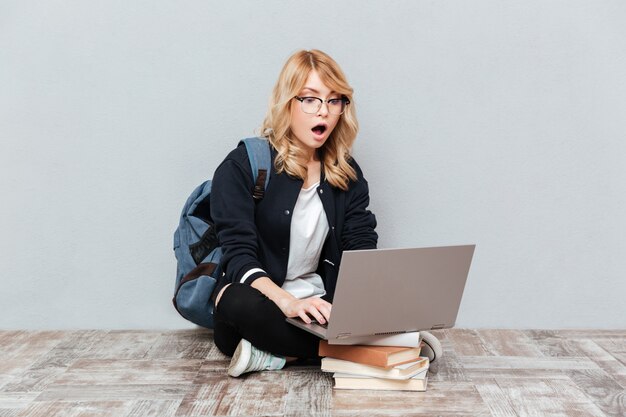 Szokujący młoda kobieta uczeń używa laptop.