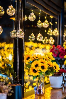 Sztuczny słonecznik w szklanym wazonie do dekoracji na bożonarodzeniowe lampki dekoracyjne w kształcie na tle bokeh dekoracja na boże narodzenie i nowy rok.