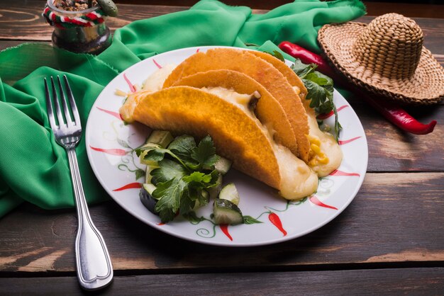 Taco wśród warzyw na naczyniu w pobliżu chili i sombrero z serwetką