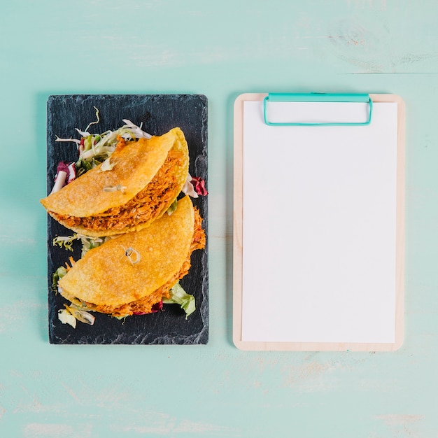 Bezpłatne zdjęcie tacos i schowek na błękitnym tle