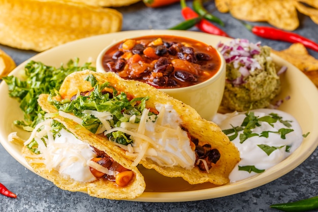 Tacos z chili con carne, sałatką, serem i kwaśną śmietaną, selektywne focus.