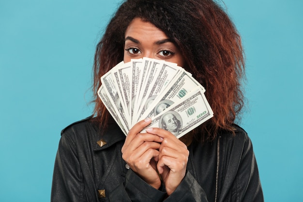 Bezpłatne zdjęcie tajemnicza afrykańska kobieta w skórzanej kurtce chowa się za pieniądze