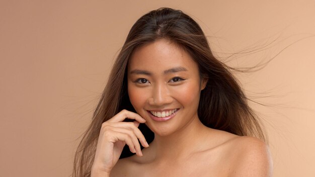 Tajski model azjatycki z naturalnym makijażem na beżowym tle