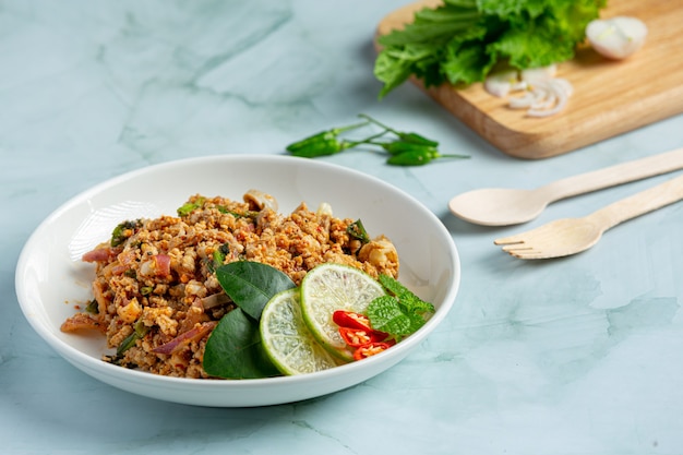 Tajskie jedzenie z pikantną mieloną wieprzowiną podawane z dodatkami