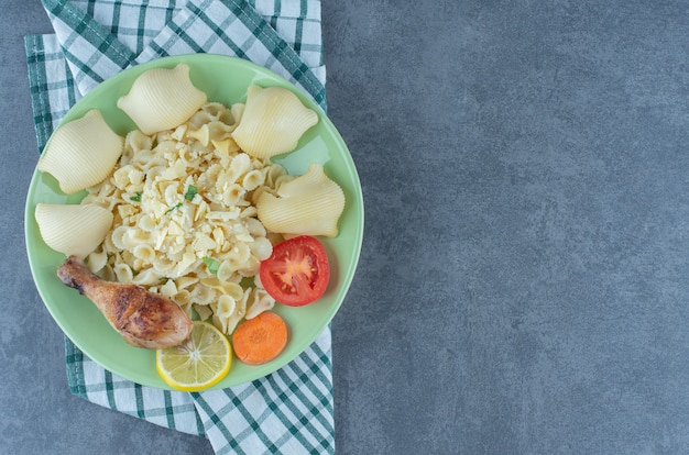 Talerz Gotowanego Makaronu I Podudzie Z Kurczaka Na Kamiennej Powierzchni.