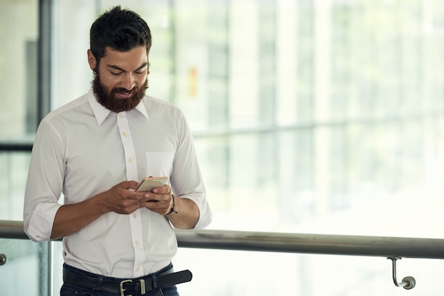 Talia w górę strzału biznesowy mężczyzna w białej koszula używa jego smartphone przy przerwą