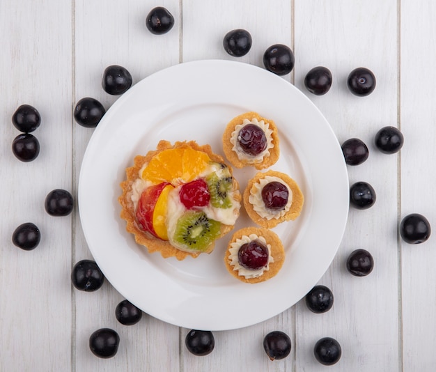 Tartlets Widok Z Góry Z Wiśniami, Kiwi I Pomarańczy Na Talerzu Z Czereśniami Na Białym Tle