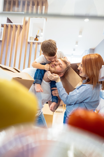 Tata mama i synek bawią się w sypialni papierowymi pudełkami