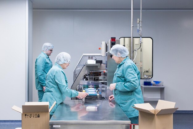 Technicy farmaceutyczni pracują w sterylnych warunkach pracy w fabryce farmaceutycznej Naukowcy w odzieży ochronnej