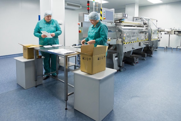 Technicy farmaceutyczni pracują w sterylnych warunkach pracy w fabryce farmaceutycznej Naukowcy w odzieży ochronnej