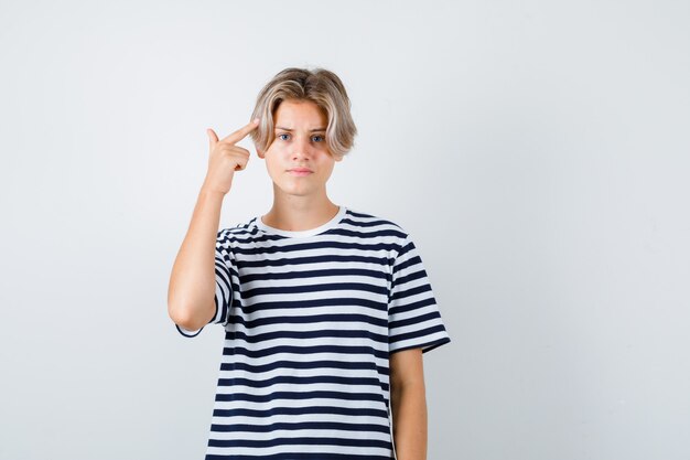 Teen chłopiec pokazując gest samobójczy w koszulce i patrząc na zirytowanego. przedni widok.