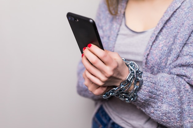 Teen Girl z łańcuchem zablokowane ręce za pomocą smartfona na białym tle