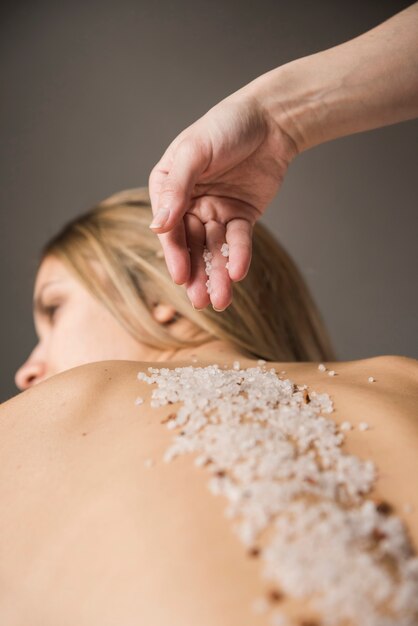 Terapeuta stosowania soli na plecach młodej kobiety