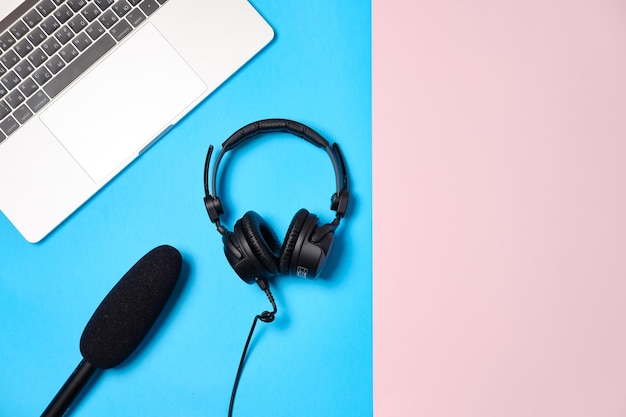 Tło muzyczne lub podcastowe ze słuchawkami, mikrofonem, kawą i laptopem na różowym stole leżącym płasko Widok z góry płasko leżący