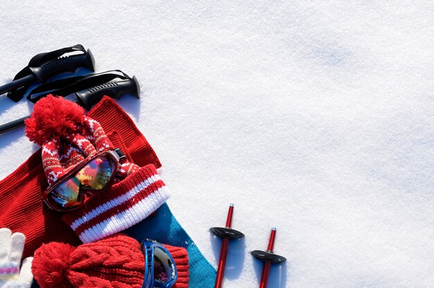 Tło zima śnieg sportowy z kijki narciarskie, okulary, czapki i rękawiczki z lato.