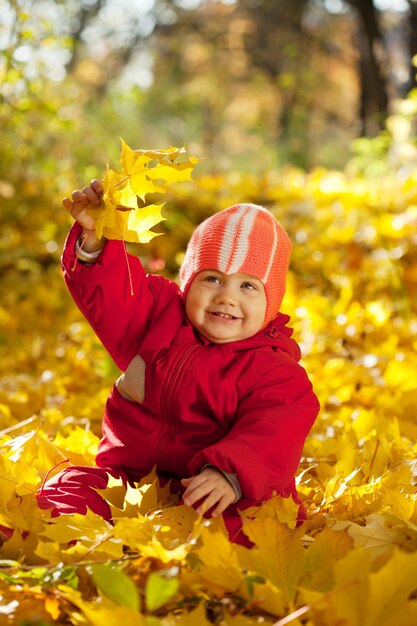 Toddler siedzi na liści klonu