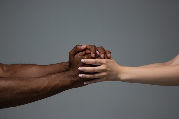 Tolerancja rasowa. Szanuj jedność społeczną. Afrykańskie i kaukaski ręce gestykuluje na szarym tle
